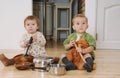 two little kids boy and girl sitting on the kitchen floor playing with pots Royalty Free Stock Photo