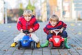 Two little kids boys in colorful clothes and rain boots driving toy cars. Twins making competition, outdoors. Active Royalty Free Stock Photo