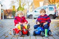 Two little kids boys in colorful clothes and rain boots driving toy cars. Twins making competition, outdoors. Active Royalty Free Stock Photo