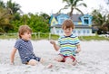 Two little kids boys having fun with building sand castle on tropical beach, happy best friends playing. Siblings Royalty Free Stock Photo