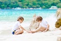 Two little kids boys having fun with building a sand castle on tropical beach of Seychelles. children playing together Royalty Free Stock Photo