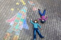 Two little kids boys having fun with drawing universe and space shuttle picture with colorful chalks. Creative leisure