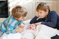 Two little kids boys with newborn baby girl, cute sister. Siblings. Brothers and baby playing with colorful toys and Royalty Free Stock Photo