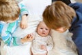 Two little kids boys with newborn baby girl, cute sister. Siblings. Brothers and baby playing with colorful toys and