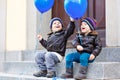 Two little kids boys playing with blue air balloons outdoors. Happy twins and toddler brothers smiling and laughing Royalty Free Stock Photo