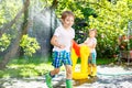 Two little kids boys playing with a garden hose water sprinkler Royalty Free Stock Photo