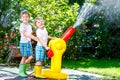 Two little kids boys playing with a garden hose water sprinkler Royalty Free Stock Photo