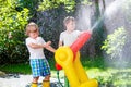 Two little kids boys playing with a garden hose water sprinkler Royalty Free Stock Photo