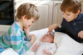 Two little kids boys playing with newborn baby sister girl