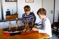 Two little kids boys playing with sailing ship model indoors. Excited children, siblings and best friends with yacht Royalty Free Stock Photo