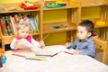Two little kids drawing with colorful pencils in preschool at the table. Royalty Free Stock Photo