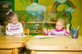 Two little kids drawing with colorful pencils at the table in Montessori preschool class. Little girls sisters in kindergarten