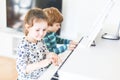 Two little kids girl and boy playing piano in living room or music school. Preschool children having fun with learning Royalty Free Stock Photo