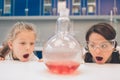 Two little kids in lab coat learning chemistry in school laboratory. Young scientists in protective glasses making