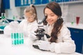 Two little kids in lab coat learning chemistry in school laboratory. Young scientists in protective glasses making