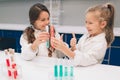 Two little kids in lab coat learning chemistry in school laboratory. Young scientists in protective glasses making Royalty Free Stock Photo