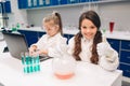 Two little kids in lab coat learning chemistry in school laboratory. Young scientists in protective glasses making