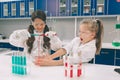 Two little kids in lab coat learning chemistry in school laboratory. Young scientists in protective glasses making Royalty Free Stock Photo