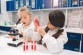 Two little kids in lab coat learning chemistry in school laboratory. Young scientists in protective glasses making Royalty Free Stock Photo