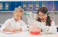 Two little kids in lab coat learning chemistry in school laboratory. Young scientists in protective glasses making