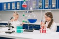 Two little kids in lab coat learning chemistry in school laboratory. Young scientists in protective glasses making Royalty Free Stock Photo