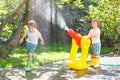 Two little kids playing with garden hose and water in summer Royalty Free Stock Photo