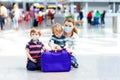 Two little kids, preschool siblings boys and mother in medical mask at airport. Children and woman, family travel by Royalty Free Stock Photo