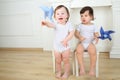 Two little kids sitting on white chairs with blue