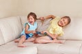 Two little mad angry girls sisters having fight at home. Friends girls can not share a gadget tablet. Lifestyle authentic funny