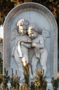 Two little marble angels reading a prayer on a gravestone