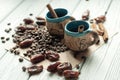 Two little old pottery handmade cups of coffee, coffee beans, sweet dried dates and cinnamon sticks