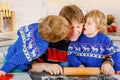 Two little preschool boys and father baking gingerbread cookies. Happy siblings, children and their dad, man in xmas