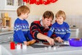 Two little preschool boys and father baking gingerbread cookies. Happy siblings, children and their dad, man in xmas