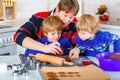 Two little preschool boys and father baking gingerbread cookies. Happy siblings, children and their dad, man in xmas Royalty Free Stock Photo