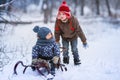Two little preschool boys sledding in the snow