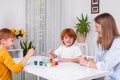 Little redhead boys with a nanny or mother or teacher sit at the table and paint with colors