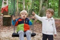 Two little sibling boys having fun in autumn forest with swing Royalty Free Stock Photo