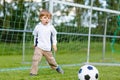 Two little sibling boys playing soccer and football on field Royalty Free Stock Photo