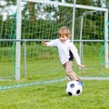 Two little sibling boys playing soccer and football on field Royalty Free Stock Photo