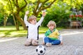 Two little sibling boys playing soccer and football Royalty Free Stock Photo