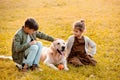 Two little siblings petting a dog and sitting on grass Royalty Free Stock Photo