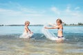 Two little sister girls fooling around in the calm sea waves splashing water to each other. Family vacation concept image Royalty Free Stock Photo