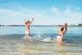 Two little sister girls fooling around in the calm sea waves splashing water to each other. Family vacation concept image Royalty Free Stock Photo