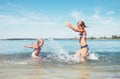 Two little sister girls fooling around in the calm sea waves splashing water to each other. Family vacation concept image