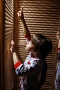 Two little sisters dressed in the pajamas are hiding in the closet with wooden doors Royalty Free Stock Photo