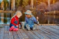 Two little sisters or friends sit with fishing rods on a wooden pier. They caught a fish and put it in a bucket. They are happy Royalty Free Stock Photo