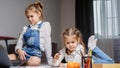 Two sisters lying on the floor at living room using laptop, playing and drawing Royalty Free Stock Photo