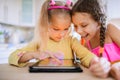 Two little sisters play on a Tablet PC Royalty Free Stock Photo