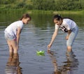 Two little sisters playing with paper boats by a river on warm a