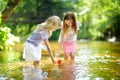 Two little sisters playing with paper boats by a river on warm and sunny summer day. Children having fun by the water. Royalty Free Stock Photo